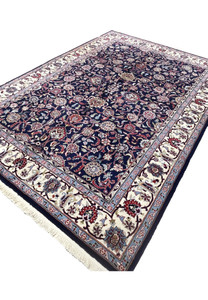Angled view of a 5'7 x 8 navy blue Persian Sarough kork rug showing dense floral field, ivory border, and deep saturated wool pile