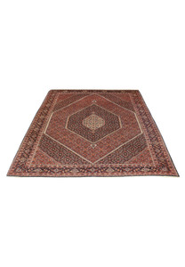 Bijar Persian iron rug laid on floor displaying dense geometric field, red ground, and symmetrical medallion design