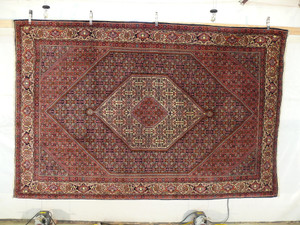 Persian Bijar iron rug hanging display showing dense weave and geometric medallion design