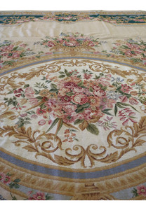 Closeup of central oval floral medallion on French Aubusson rug showing layered bouquets, scrollwork, and soft pastel color transitions