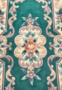 Close view of central floral motif on Aubusson Art Deco rug highlighting raised scrollwork texture and soft blush, sage, and ivory colors