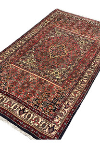 Angled perspective of a Persian Bijar rug emphasizing thick wool pile, compact structure, rug-in-rug layout, and durable construction