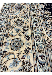 Closeup of ivory border on Persian Nain 6 LA Habibian rug featuring floral cartouches, silk highlights, and refined craftsmanship