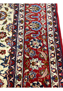 Border closeup of an Isfahan rug revealing intricate floral scrollwork, deep red and navy tones, and crisp hand-knotted silk detailing.