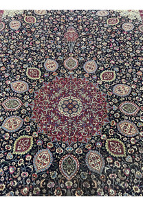 Close view of central medallion on Persian Mashad rug signed Sheshkalani, displaying detailed floral geometry, silk accents, and rich red and navy color contrast.