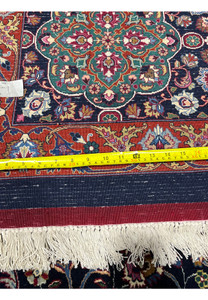 Backside of a Persian Mashad rug measured with a ruler, emphasizing accurate sizing, dense knot work, and premium kork wool and silk construction.