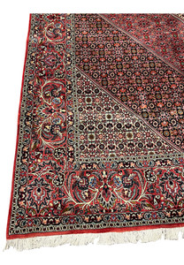 Border close-up of a Persian Bijar iron rug showing compact knot structure, crisp outlines, layered design bands, and rich traditional colors