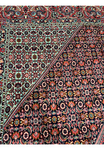 Color detail closeup of a Persian Bijar rug showing deep red, navy blue, ivory, olive green, and subtle light blue tones woven into dense wool