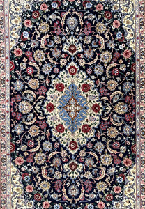 Central field of Persian Isfahan rug featuring ivory medallion, light blue arabesques, burgundy floral accents, and dense fine knot structure