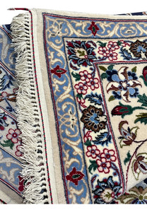 Folded corner of a 7x10 Persian Isfahan rug highlighting ivory border, floral detailing, crisp edges, and fine hand knotted construction