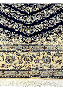 Lower border of a Persian Nain 6 La rug featuring ivory ground with floral arabesques and precise silk detailing