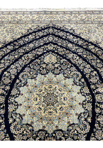 Upper section of Persian Nain 6 La rug showing navy field with scrolling floral vines and silk highlights near the top border