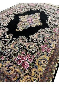 Angled view of a signed Persian Qum silk rug highlighting silk sheen, fine knotting, and detailed floral design