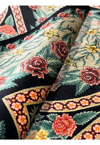 Rolled view of a signed Persian Qum silk rug highlighting flexibility, silk sheen, and continuous floral pattern flow across the field and borders