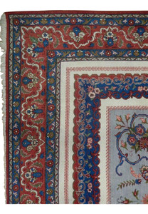 Detailed border corner of a Persian Isfahan rug featuring rich red borders, blue guard bands, floral motifs, and precise hand-knotted detail