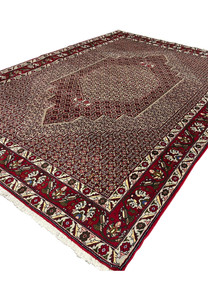 Angled view of Persian Senneh rug revealing surface texture, dense knotting, stepped medallion depth, and color contrast
