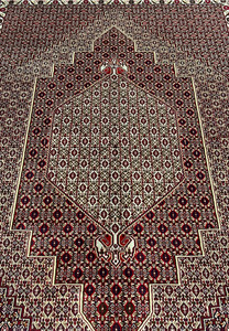 Central medallion detail of Persian Senneh rug with stepped diamond geometry, ivory framing, and dense burgundy and brown pattern fill.