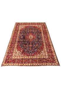 Laid down view of Persian Isfahan rug showing overall proportions, navy field contrast, brick red medallion, and classic floral border layout