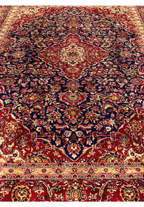 Top view of Persian Isfahan rug highlighting symmetrical floral composition, navy blue field, red medallion center, and ivory framing borders