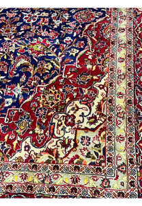 Lower inner field detail of Persian Isfahan rug featuring scrolling floral vines, navy background, ivory highlights, and subtle gold tones