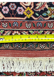 Back of Persian Bijar rug with yellow tape measure showing fine knot density and tightly woven construction