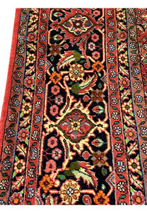 Close-up of Persian Bijar rug border with detailed floral motifs, dark navy ground, and terracotta accents