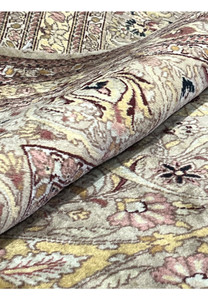 Rolled corner detail of handmade wool Agra rug showing pile thickness, flexibility, vintage wear, and soft beige gold floral weaving