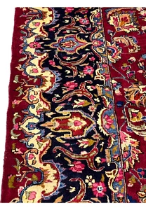 Macro border closeup showing precise knot work, floral detailing, and rich navy, ivory, and red color contrast