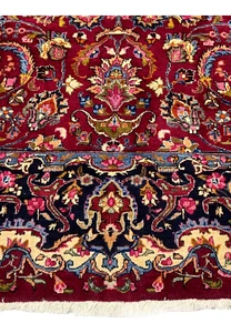Lower border detail of Persian Mashad rug with navy blue ground, ivory floral elements, and crisp hand knotted definition