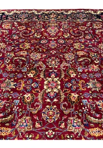 Close view of Mashad rug field showing dense floral arabesques, vibrant red background, and fine wool knotting