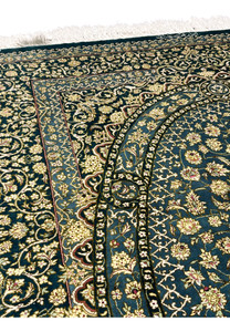 Close view of Persian Qum silk rug showing dense floral vines and arabesque motifs on teal blue field with ivory blossoms and fine 1000 KPSI knot detail