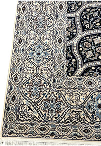 Side view showing low dense pile of Persian Nain 6 LA Kork wool rug with silk floral highlights navy dome pattern.