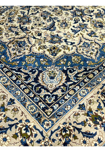 Inner border closeup of Persian Kashan rug with intricate blue floral motifs ivory outlines and symmetrical vine pattern