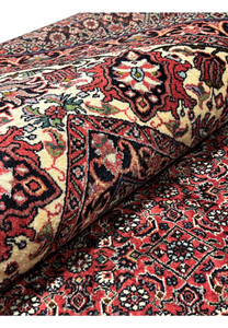 Rolled corner of Persian Bijar Iron Rug 8'2 x 11'4 revealing thick wool pile, durable foundation and richly patterned red field