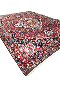 Perspective view of vintage Persian Bakhtiari area rug 10x14 with red field and ivory center medallion.