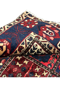 Folded corner of 7x10 hand-knotted Bakhtiari Persian rug revealing weave structure and pile height