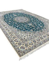 Jewel-toned emerald green Nain rug angled view showing silk highlights catching the light across the floral field