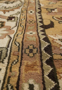 Pattern closeup with stylized palmettes serrated leaves and curling vine in soft camel and sage
