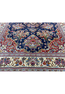 Lower field of Persian Qum kork rug showing brick red corner spandrel and floral vase bouquet motif