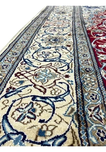 Border close-up of Persian Nain rug highlighting ivory ground, scrolling vines, and navy floral elements