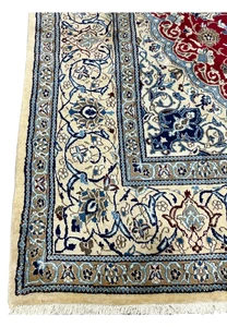 Close view of ivory border on red Persian Nain rug with scrolling floral motifs and fine symmetrical drawing