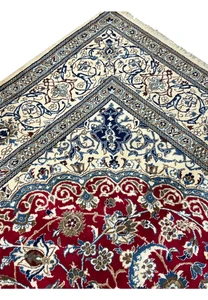 Inner border detail of Persian Nain rug with repeating floral motifs, navy outlines, and precise hand knotted structure