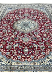 Midfield detail of red Persian Nain rug with dense floral vines, silk highlights, and precise hand knotted pattern
