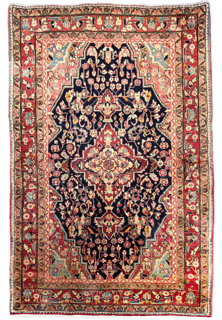 A full view of a 4'3" x 6'5" Vintage Persian Sarough Rug with intricate floral designs and a deep navy blue central field surrounded by borders of cream, crimson, and sage.