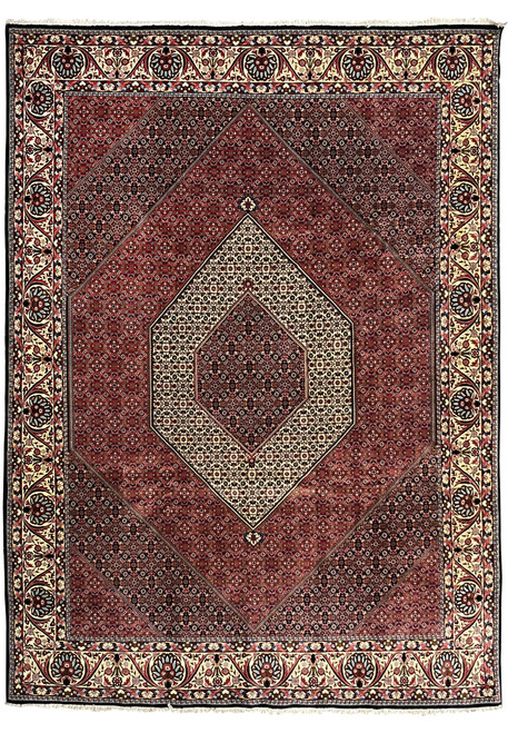 Full view of a large Persian Bijar iron rug with diamond medallion, dense red field, and wide ivory floral border