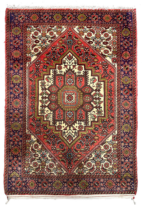 Hand-knotted Persian Gholtogh rug with bold geometric medallion, brick red field, ivory accents, and navy tribal border, full view