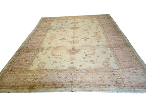 Angled studio view of ivory and shrimp Oushak rug showing full floral field and border