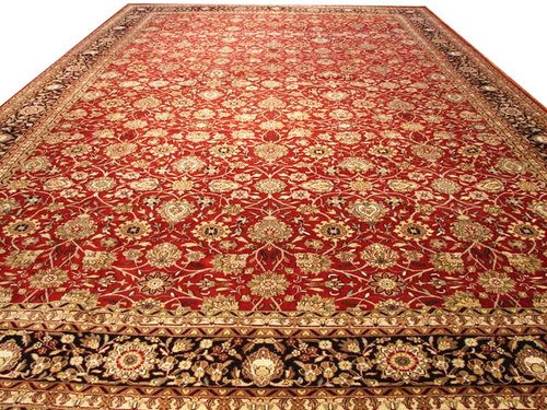 Oversize red Sarouk design rug at an angle showing dense ivory and gold floral drawing