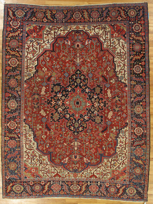 8'4" x 11' antique Persian Heriz rug shown flat with rust red field and navy medallion