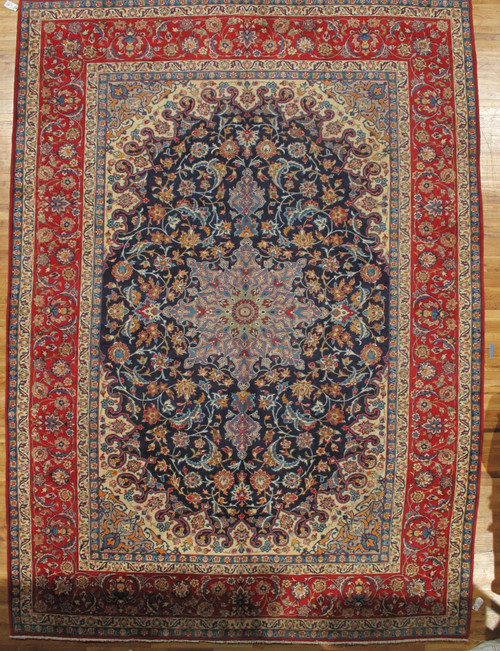 Full overhead view of the navy Isfahan rug with red floral border on a wooden floor